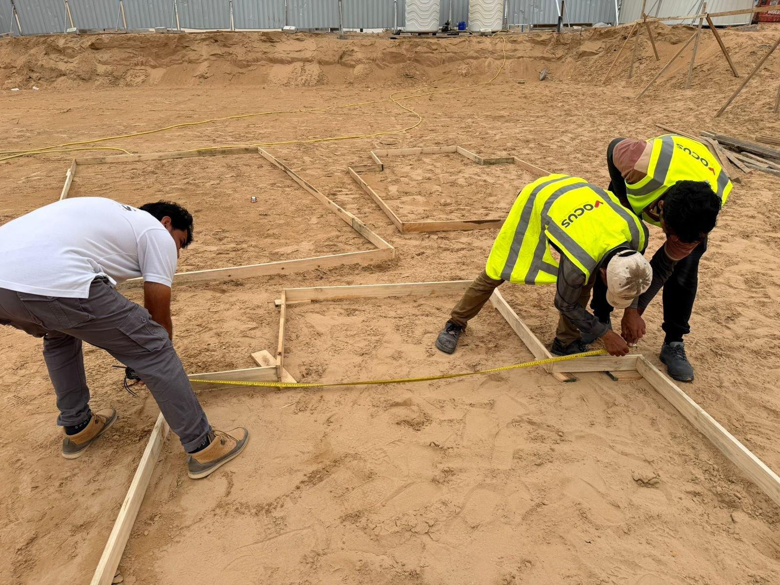 Vocus site team setting out foundation lines with tape and timber profile boards, Al Aweer First, Dubai